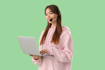 Canvas Print - Teenage girl in headset with laptop working online on green background