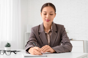 Wall Mural - Young Asian businesswoman working at her workspace in office