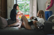 © Daniel Gonzalez/Stocksy - Young women relaxing, playing guitar and smoking at home