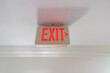 © Alvaro Lavin/Stocksy - Red Exit Sign Hanging on White Ceiling in New York