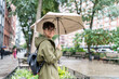 © Alvaro Lavin/Stocksy - Woman holding umbrella walking in New York City during rainy day