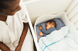 © Diego Martin/Stocksy - Mother Putting Baby to Bed in Crib at Night