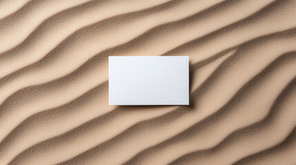 Poster - blank card resting on textured sand, showcasing gentle waves and shadows. interplay of light and texture creates serene and minimalist aesthetic