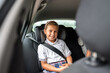 © Alvaro Lavin/Stocksy - Smiling schoolgirl wearing seat belt sitting in car going to school