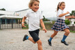 © Alvaro Lavin/Stocksy - Two happy school kids running outside their school