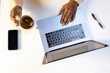 © Jimena Roquero/Stocksy - Crop of anonymous man's hands using laptop and holding tea cup