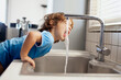 © Nasos Zovoilis/Stocksy - Young boy drinks water directly from kitchen sink at home