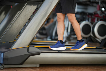 Close up man feet running on the treadmill at the gym. Cardio exercise