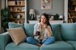 © Mihajlo Ckovric/Stocksy - Woman Relaxing on Sofa with Coffee and Smartphone at Home