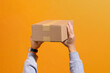 © Marc Tran/Stocksy - Hands Holding Cardboard Box Against Orange Background