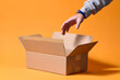 © Marc Tran/Stocksy - Hand Reaching Into Open Cardboard Box on Orange Background