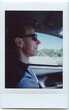© Rachel Schmidt/Stocksy - Instax Photo of Man Driving with Sunglasses on