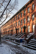 © Yakov Knyazev/Stocksy - Snow-covered urban street lined with historic brick townhouses.