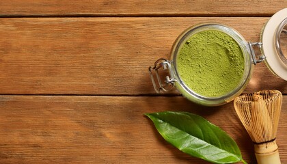 Wall Mural - Matcha powder in a glass jar, accompanied by a whisk and fresh leaves.