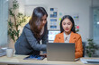 © amnaj - Two businesswomen working together using laptop in modern office