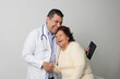 © Arlette - Elderly 80-year-old Latin woman visits the dark-skinned geriatric specialist medical doctor to check her health, they greet each other, laugh and hug