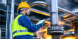 © AnuStudio - Geothermal Energy Concept. A worker in safety gear monitors equipment on a tablet in an industrial facility with pipes and steam in the background.
