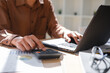 © ijeab - Accountant working on financial calculations using a calculator and laptop for business analysis.