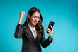 © Kawee - Asian excited woman looking at mobile phone in isolated blue background.