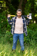 Wall Mural - Lumberjack in the forest. Man with ax. Serious lumberjack. Bearded man with ax in hands. Bearded lumberjack. Lumberjack worker.