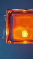 Poster - a close-up of luminous orange glows within glass-like squares surrounded by cool blues.