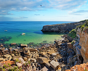 Wall Mural - rocky coastline, ocean and sunlight shines through gaps in clouds. beautiful nature background.