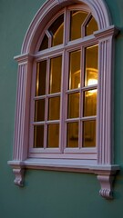 Leinwandbilder - a pastel pink arched window on a pale green wall, framed by warm evening light.