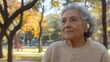 © Nadin Faust - Elderly woman enjoys a peaceful moment in a sunlit park surrounded by golden autumn leaves and vibrant trees