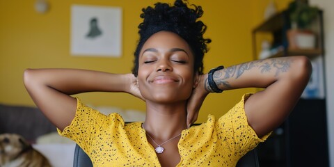 Wall Mural - A woman is sitting in a chair with her arms crossed and a smile on her face. She is wearing a yellow shirt and a necklace