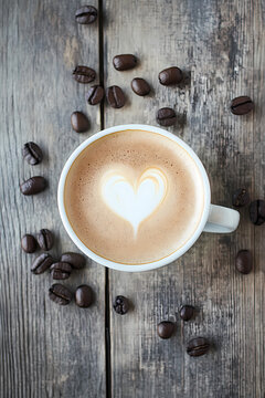 A cup of coffee with latte art on a wooden background, a top-view composition, coffee beans scattered around the table, a coffee texture