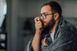 © Ljustina - Sick man using inhaler at home, wrapped in blanket