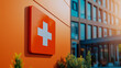 © Madlen Gray - Red medical cross on building facade in sunlight, healthcare symbolism