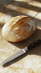 Poster - Close-up of a fresh, crusty loaf resting on a rustic wooden surface beside a sharp knife in soft natural light
