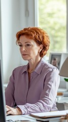 Aufkleber - Middle-aged woman working at a desk in a bright office while focusing on her computer
