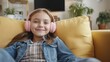 © vadosloginov - Joyful young girl enjoying music on a cozy couch in a bright living room