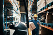 © Davor - Smiling male worker using smartphone and carrying box in large warehouse