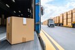 © Moopingz - Cardboard box on conveyor belt, at truck's open door, other trucks blurred in background.