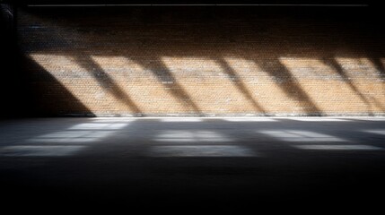 Poster - Dark interior of a deserted industrial warehouse features weathered brick walls and a worn concrete floor, with light casting dramatic shadows throughout the space