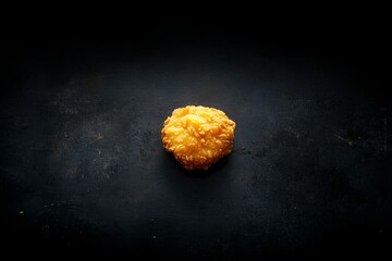 Poster - A single crispy fried chicken tender rests on a black stone table, highlighted by soft light, with ample space alongside for text or complementary ingredients