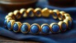 © TITISCAHYA - Gold-blue gemstone bracelet on silk, wooden background