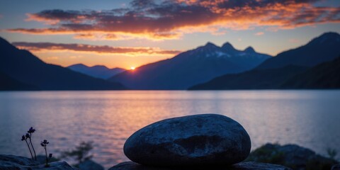 Poster - tranquil sunset over mountain lake with silhouette stone in foreground soft focus ideal for backgrou