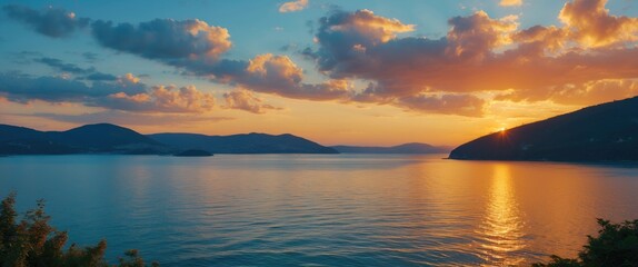 Wall Mural - golden sunset reflections over calm bay waters with distant blue hills creating a serene summer even