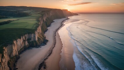 Poster - aerial view of serene beach and majestic coastal cliffs at sunset illuminating the ocean waves and l