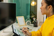 © Gybziii - A woman in a yellow sweater is sitting at a desk with a computer monitor and a clipboard. She is smiling and she is happy