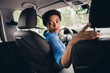 © deagreez - Young woman confidently driving a car, demonstrating focus and skill, while enjoying a casual drive through an urban city street