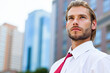 © Minerva Studio - Young businessman looking up in modern city center