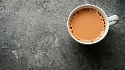 Poster - A beautifully composed warm beverage of rich brown color rests in a white cup on a textured stone surface, evoking sensations of coziness and comfort typical of a serene morning