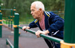 © caftor - Sportive elderly man doing street fitness on the simulator in park