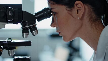 Poster - Laboratory research montage shows a focused female scientist looking through a microscope, analyzing samples in a modern laboratory setting, captured in slow motion