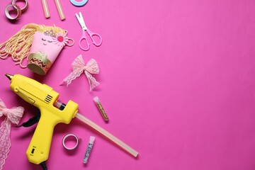 Wall Mural - Hot glue gun and handicraft materials on bright pink background, flat lay. Space for text